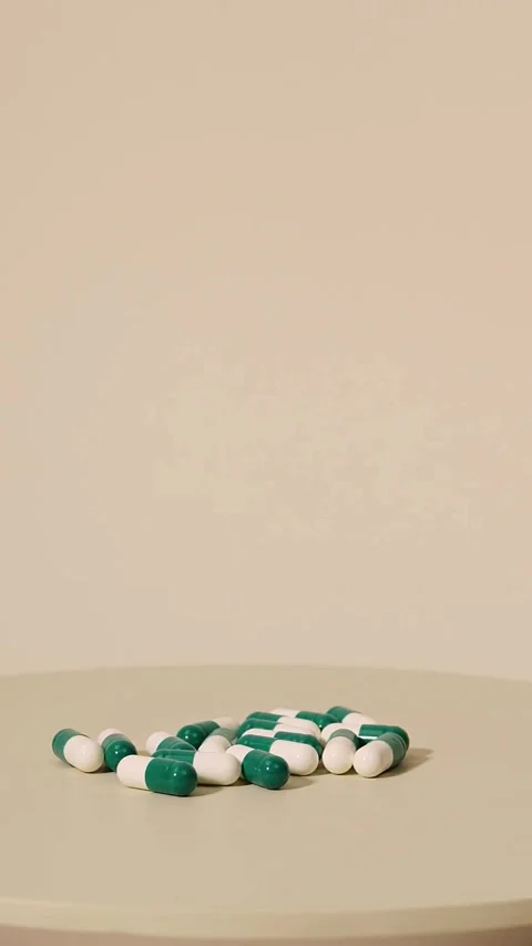 Green and white capsules piled on a light table 库存影片 331773697