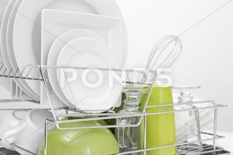 Green and white dishes drying on dish rack Stock Photos
