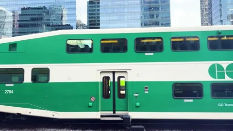 A green and white double-decker commuter train drives past modern glass. Stock Footage 334583821