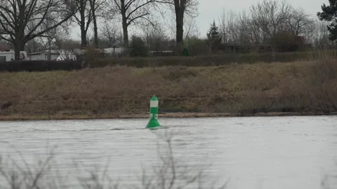 Green and white navigation buoy floating in the middle of a wide river. Stock Footage 326961847