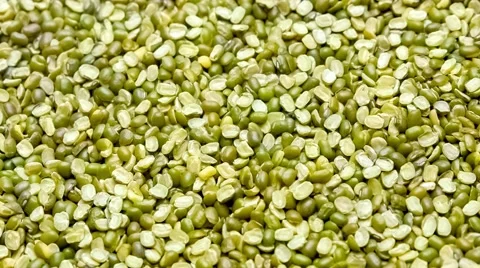 Green and yellow split mung beans being scooped up with rustic wooden spoon Stock Footage 65226210