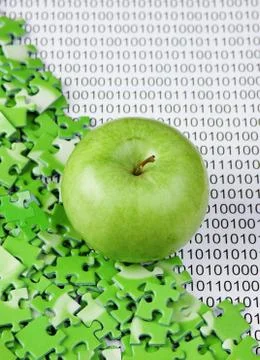 Green apple and puzzles on a binary code 库存照片