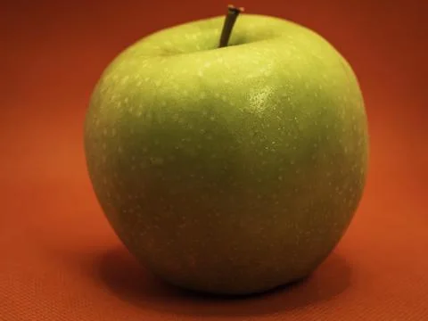 A green apple and a red background Stock Photos