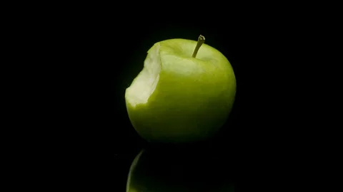 A green apple with a bite out rotating on a black background Stock Footage 128721607