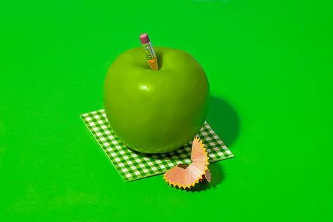 Green apple on check pattern cloth near pencil shavings Stock Photos