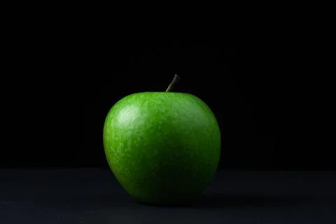 Green apple on a dark background. A cut green apple on a black background. Stock Photos