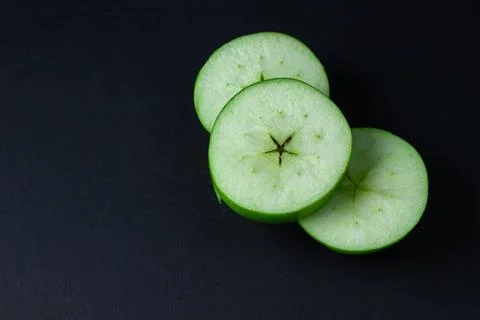 Green apple on a dark background. A cut green apple on a black background. Stock Photos
