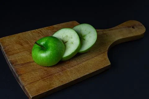 Green apple on a dark background. A cut green apple on a cutting board on a blac Stock Photos