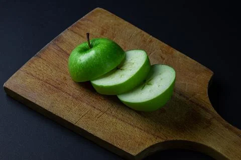 Green apple on a dark background. A cut green apple on a cutting board on a blac Stock Photos