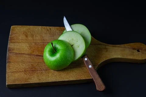 Green apple on a dark background. A cut green apple on a cutting board on a blac Stock Photos