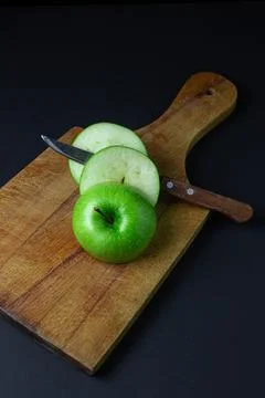Green apple on a dark background. A cut green apple on a cutting board on a blac Stock Photos