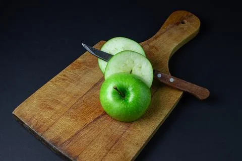 Green apple on a dark background. A cut green apple on a cutting board on a blac Stock Photos