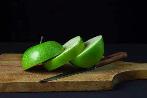 Green apple on a dark background. A cut green apple on a cutting board on a blac Stock Photos