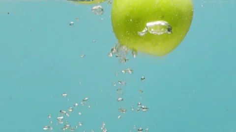 Green apple falling in boiling water, fresh sliced fruits and vegetables falling Stock Footage 243136091
