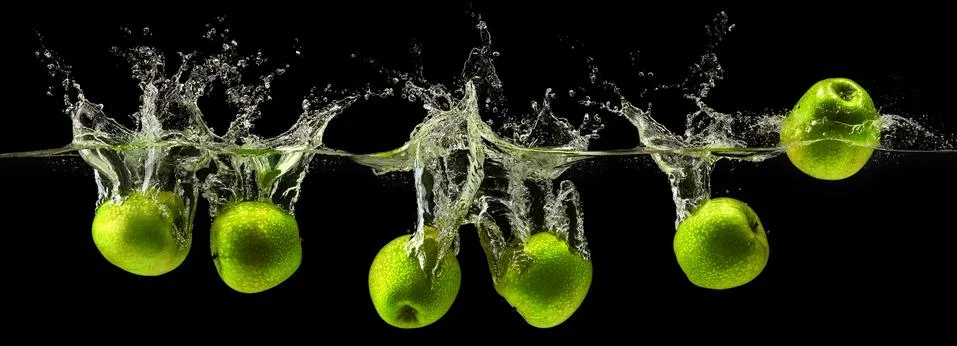 Green apple falling in water on black background Stock Photos