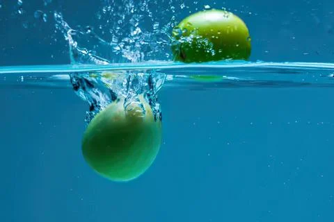 Green apple falling into water with splash and bubbles Stock-Fotos