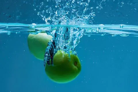 Green apple falling into water with splash and bubbles Stock-Fotos