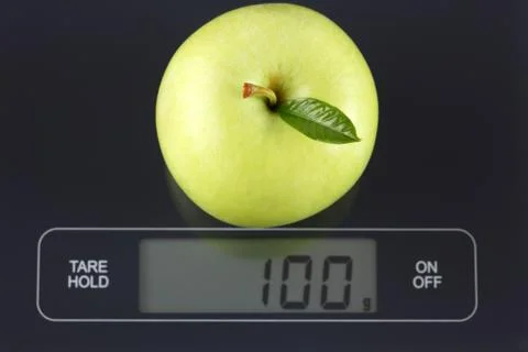 Green apple on kitchen scale Stock Photos