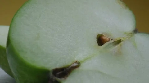 Green apple macro shooting,isolated half apple on yellow background rotates Stock Footage 130997250