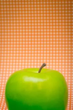 Green Apple on Orange Background Stock Photos