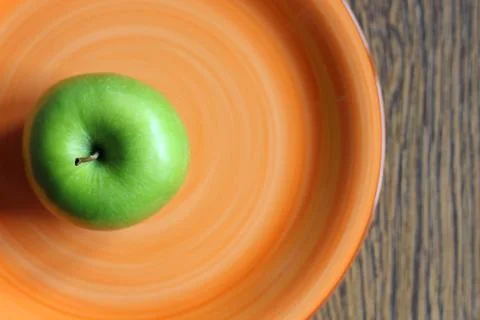 Green apple on an orange plate Stock Photos