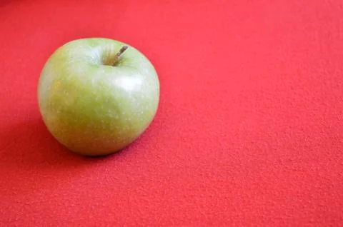 Green apple on a red background Stock Photos