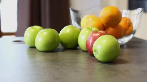 A green apple rolls on the table, and then stands next to other fruits. Stock Footage 112939486