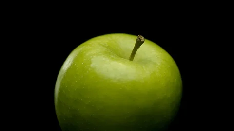 A green apple rotating on a black background Stock Footage 128721750