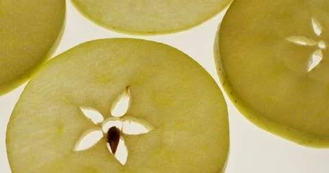 Green Apple slices rotating on a bright white background. Close up view, shot on Stock Footage 107928528