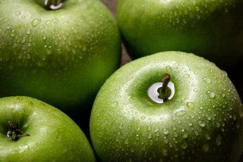 Green apples with drops on dark background Stock Photos