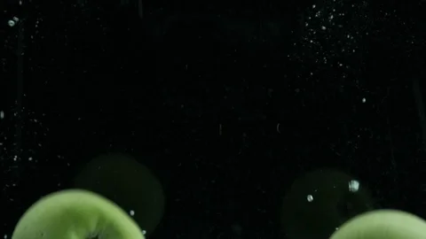 Green apples fall into clear water with bubbles Stock Footage 125812545