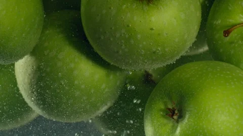 Green apples fall down in water against black background, super slow motion Stock Footage 97439967