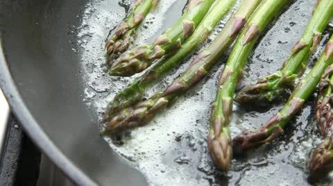 Green asparagus being fried in a pan of butter Stock Footage 24672273