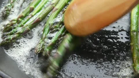Green asparagus being fried in a pan of butter Stock Footage 24672277