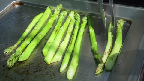Green asparagus being fried in a pan. A cook is stirring asparagus. Video stock 85290341
