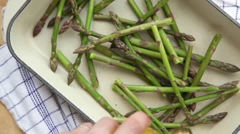 Green asparagus in a roasting tin being drizzled with oil Stock Footage 24672279