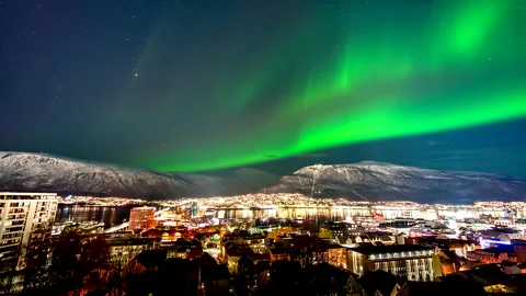Green aurora borealis dance in night sky over illuminated Tromso city, timelapse Stock Footage 324695036