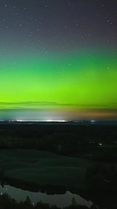 Green aurora borealis timelapse over Latvia rural landscape with city lights on Vidéo 336721636