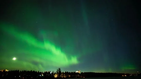 Green aurora northern light dancing under a starry and moonlit sky on a frozen l Stock Footage 152947631