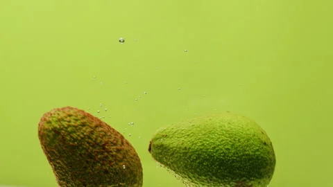 Green avocado dropping in water, fresh fruits and vegetables falling splashing Stock Footage 241753068