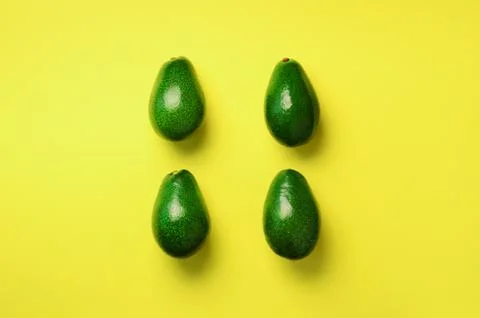 Green avocado pattern on yellow background. Top view. Pop art design, creative Stock Photos