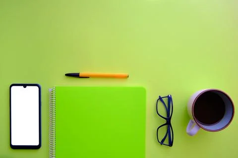Green background with cell phone, notebook, coffee and glasses Stock Photos