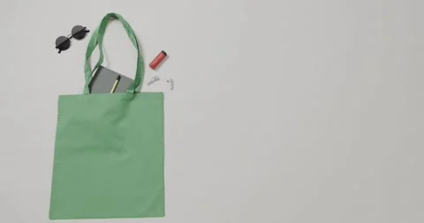 Green bag with sunglasses, notebook, lipstick on white background, copy space, Stock Footage 331447596