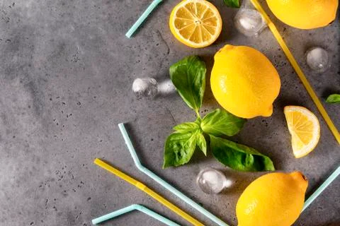 Green Basil sprigs, ice cubes, juice yellow lemons,   yellow and blue tubes o Stock Photos