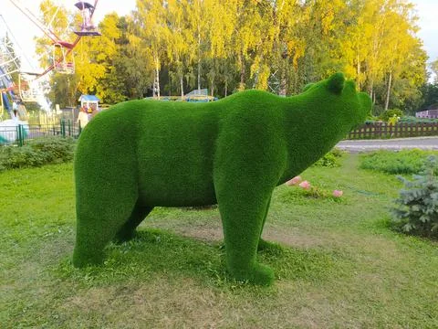 Green bear made of artificial grass green on the background of trees. Stock Photos