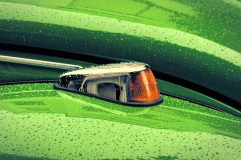 Green Beatle's orange blinker with raindrops. Stock Photos