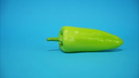 Green bell pepper comes in the middle of the frame, rotating  and running away Stock Footage 314342519