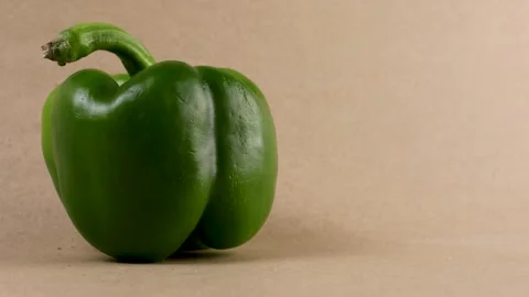 Green bell pepper placed on a neutral-toned background with directional Video stock 308922405