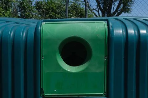 Green bin in front ouf trees under blue sky in france Stock Photos