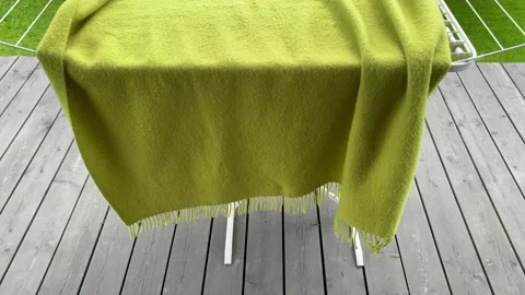 Green blanket draped over rack in bright setting Vídeo Stock 343864743